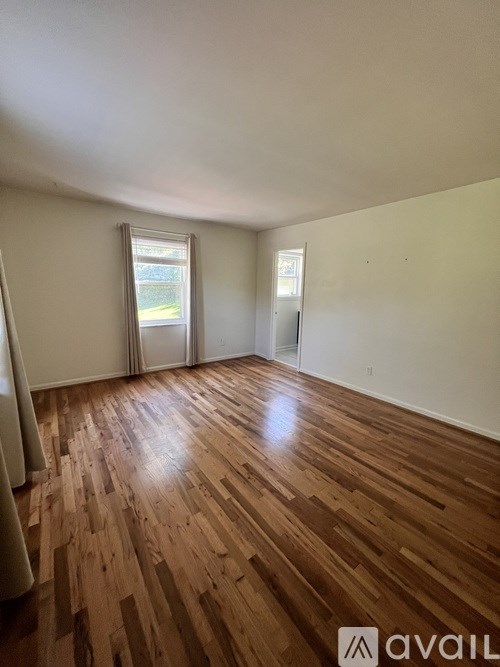 A room with wooden flooring and a window with a view of a body of water.