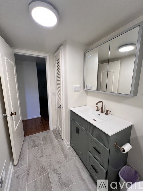 A bathroom with a sink, mirror, and light.