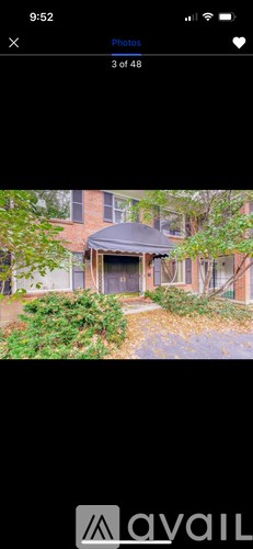 A house with a black roof and a tree in front.