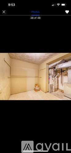 A room with a white ceiling and walls, a wooden floor, and a window with a view of a building outside.