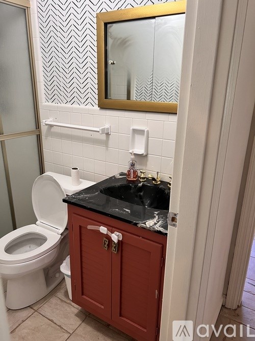 A bathroom with a toilet, sink, and mirror.