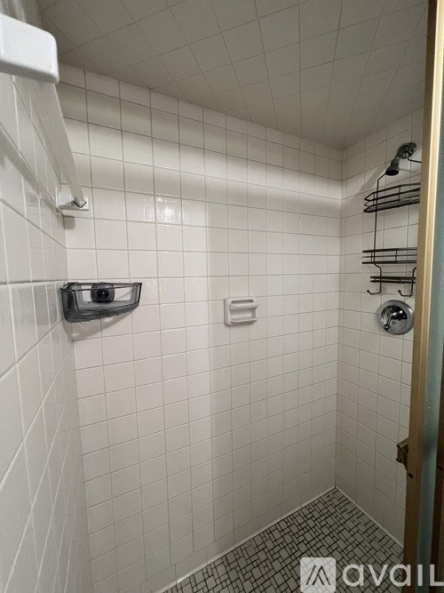 A white tiled bathroom with a towel bar and a towel rack.