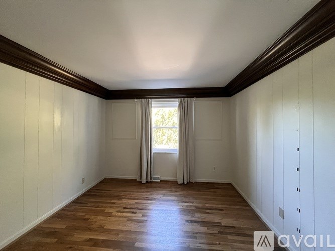 A room with wooden floors and white walls is available for rent.
