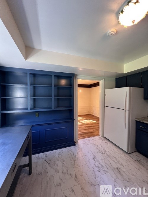 A kitchen with a white fridge and a blue cabinet.