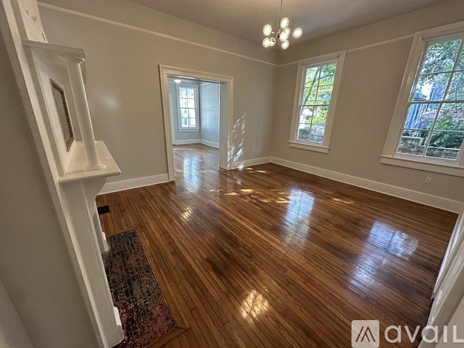 A room with wooden floors and white walls, with a window on the right side.