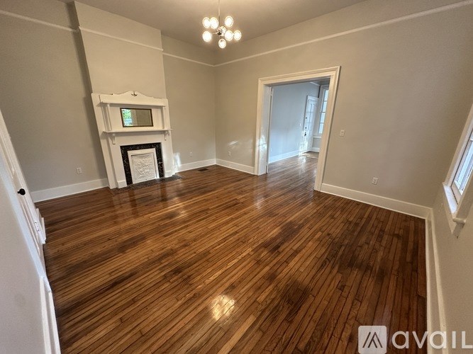 A room with wooden flooring and a fireplace with a TV above it.
