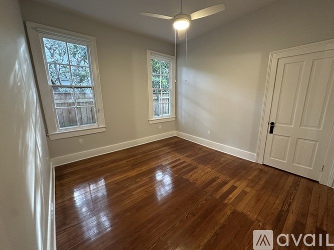 A room with wooden floors and two windows.