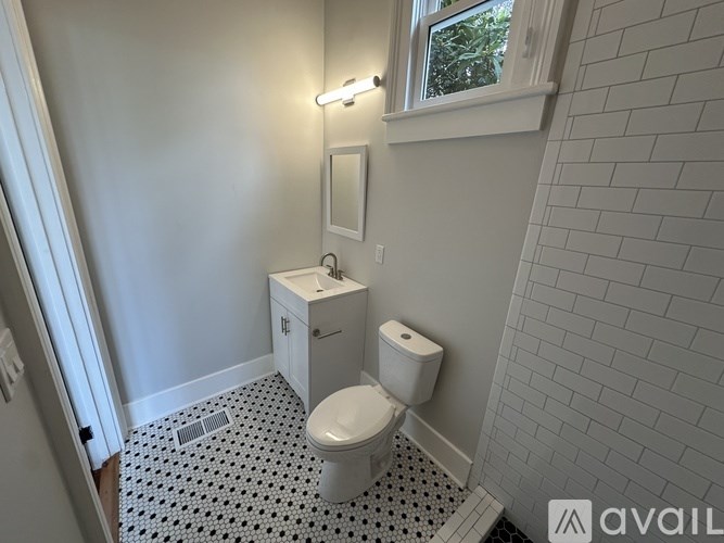 A bathroom with a toilet, sink, and a window.