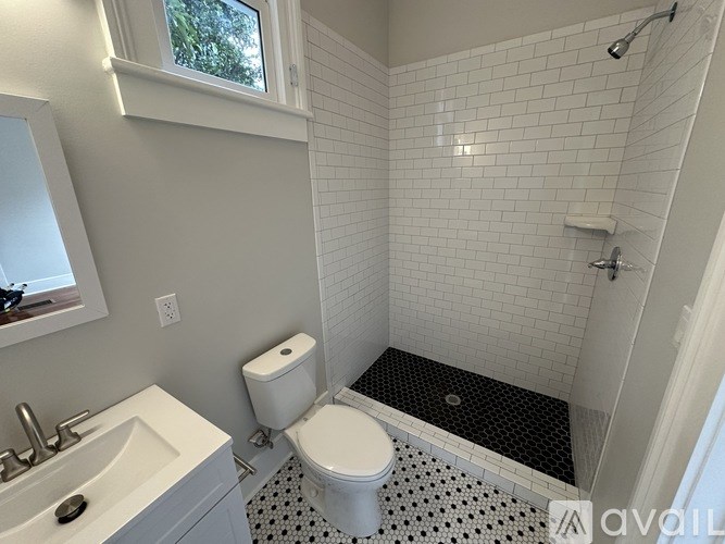 A white toilet sits in a bathroom with a black and white floor mat.