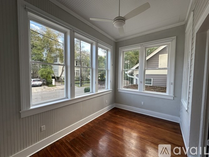 A room with a fan and wood flooring.