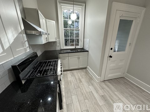 A kitchen with a black countertop and stove top oven.