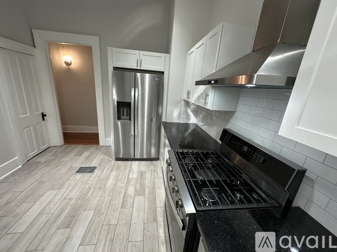 A kitchen with a stainless steel refrigerator and a black stove top oven.