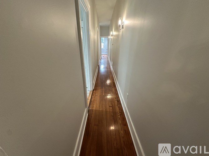 A long hallway with wooden floors and white walls.