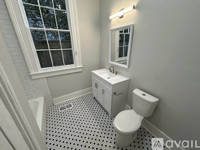 A bathroom with a toilet, sink, and window.