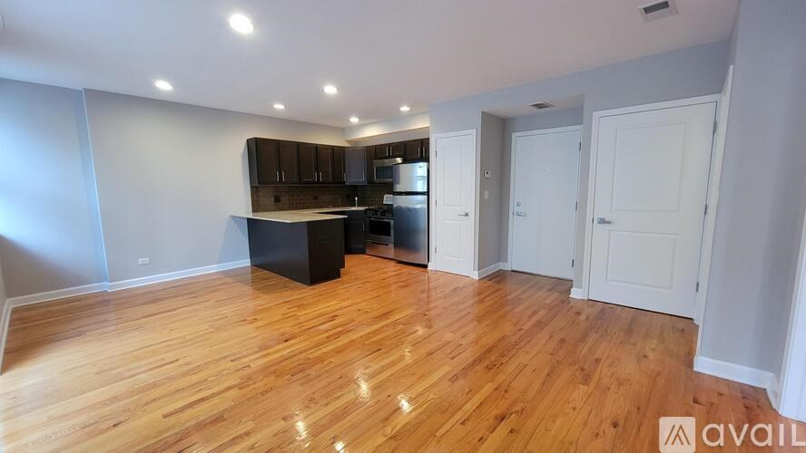 A spacious kitchen with wooden floors and white walls.