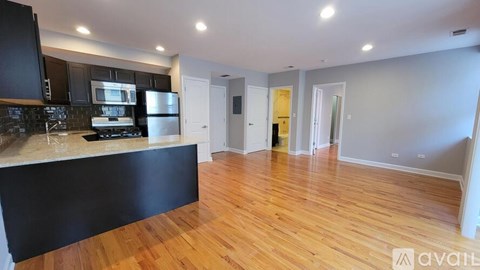 A kitchen with black cabinets and a wooden floor.