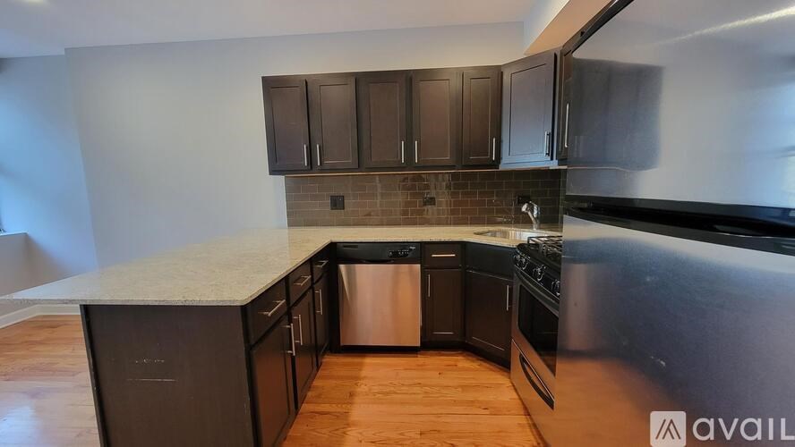 A kitchen with dark brown cabinets and a stainless steel dishwasher.