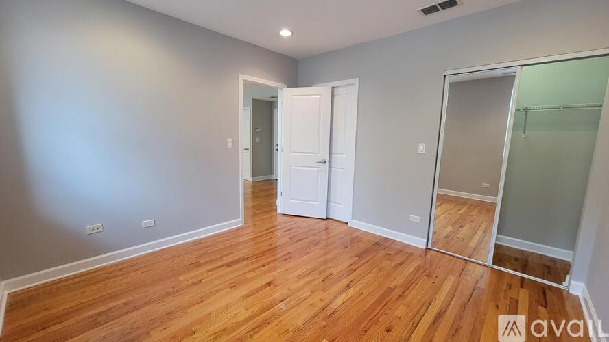 A room with wooden floors and white walls, with a door on the left and a glass door on the right.