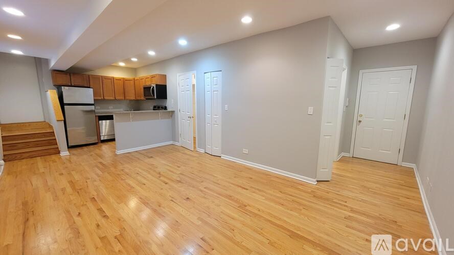 A room with wooden flooring and a kitchen area with stainless steel appliances.