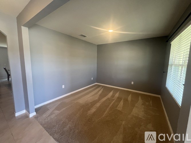 A room with a carpeted floor and a window with blinds.