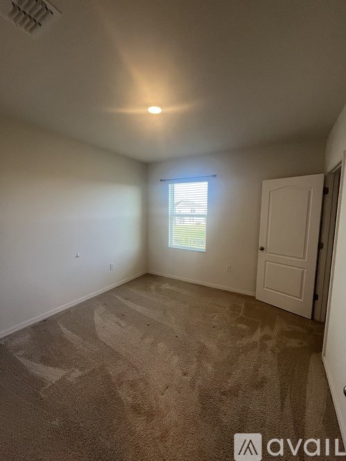 A room with a carpeted floor and a window with blinds.