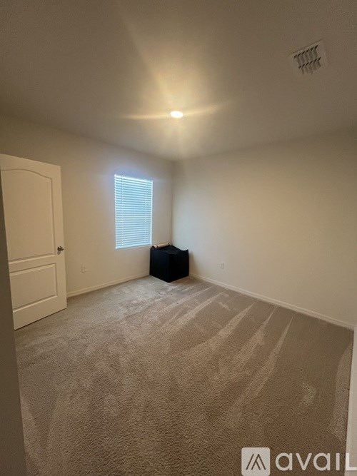 A room with a carpeted floor and a window with blinds.