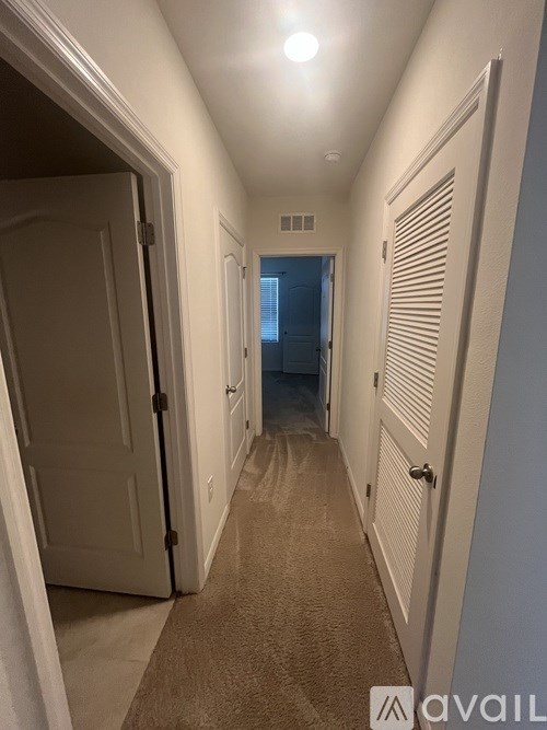 A hallway with white walls and a carpeted floor.
