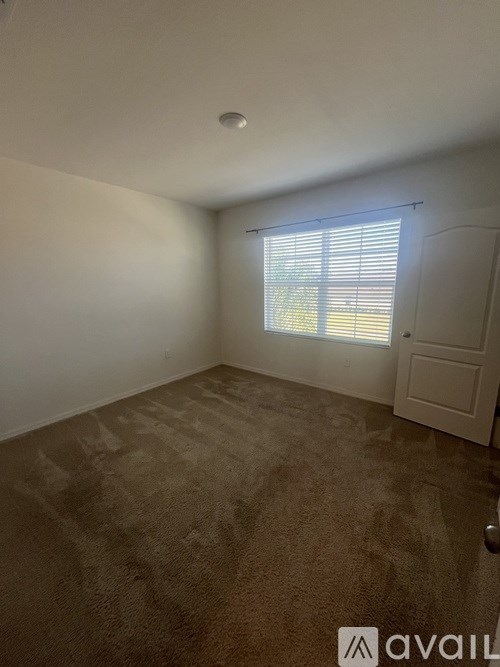 A room with a carpeted floor and a window with blinds.