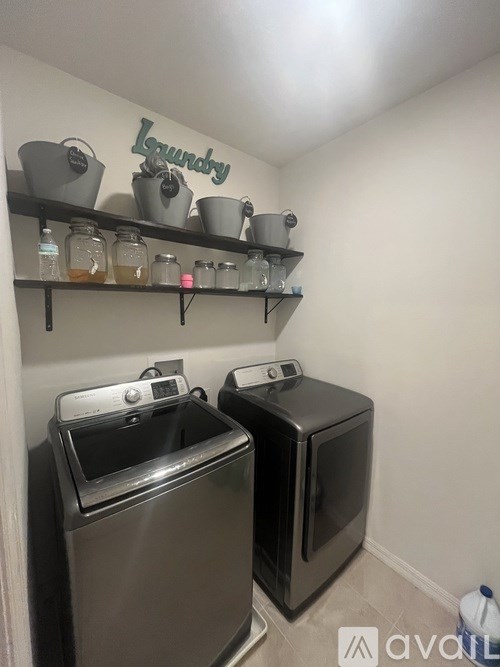 A laundry room with two washing machines and shelves with containers on them.