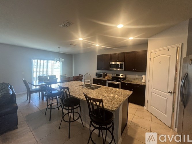 A kitchen with a granite countertop and bar stools.