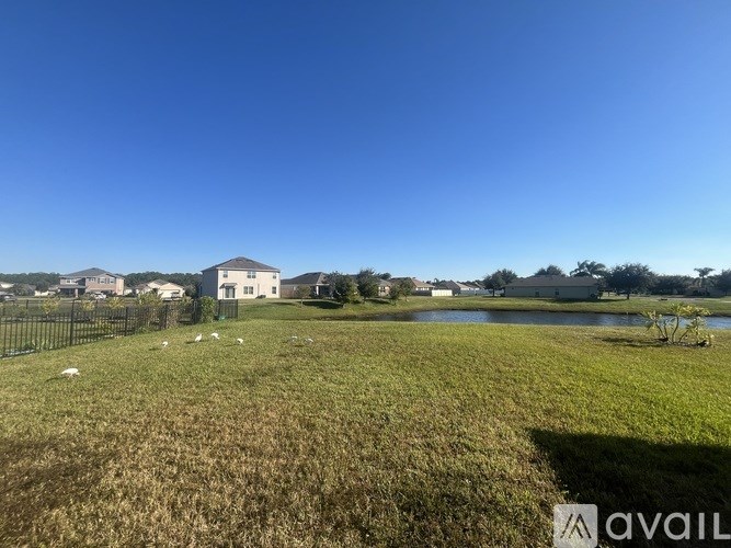 A grassy field with a house and a lake in the background.