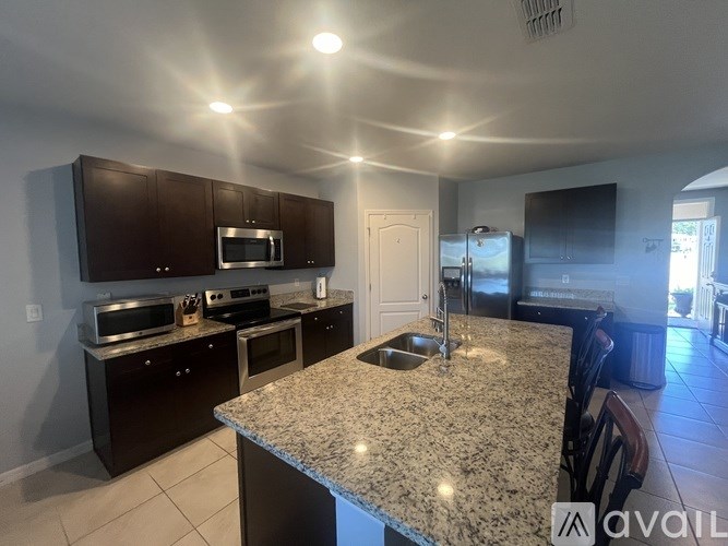 A kitchen with granite countertops and dark brown cabinets.