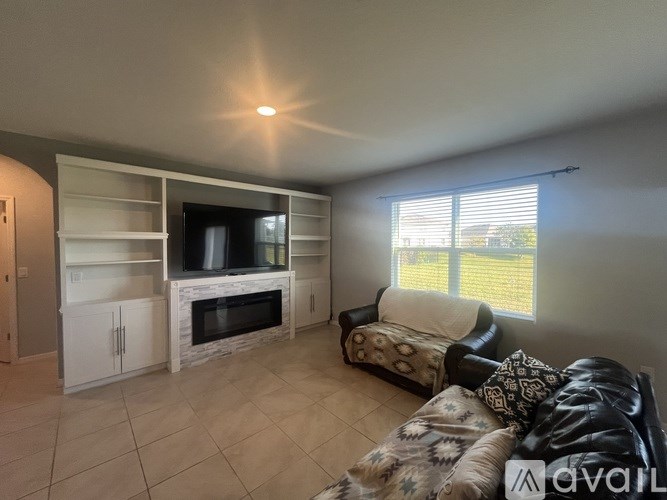 A living room with a television, couch, and a fireplace.
