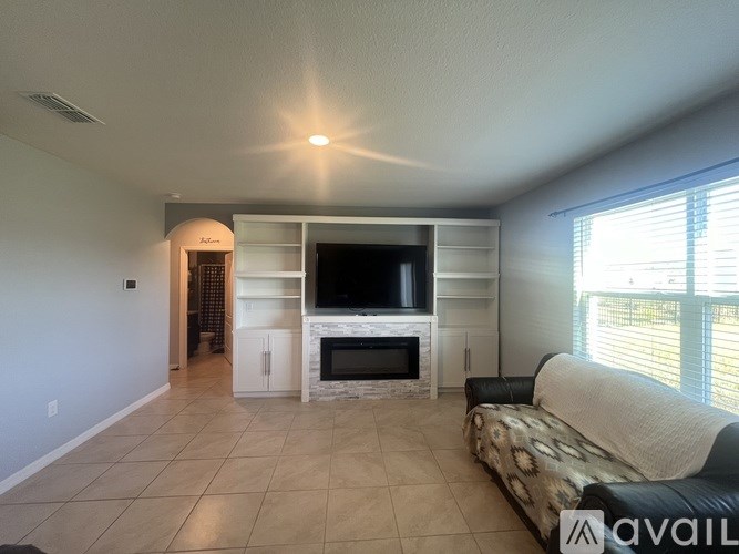 A living room with a television, couch, and fireplace.