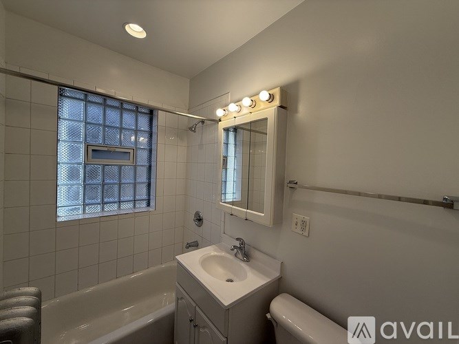 A bathroom with a white sink, a bathtub, and a window with bars.