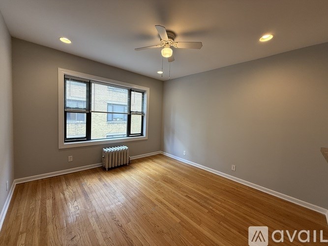 A room with a ceiling fan and a window with a radiator beneath it.