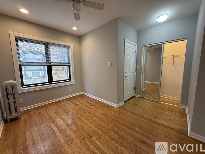 A room with wooden flooring and a window with blinds.