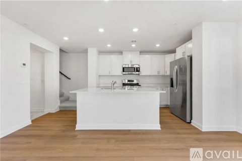 A modern kitchen with white cabinets and a wooden floor.