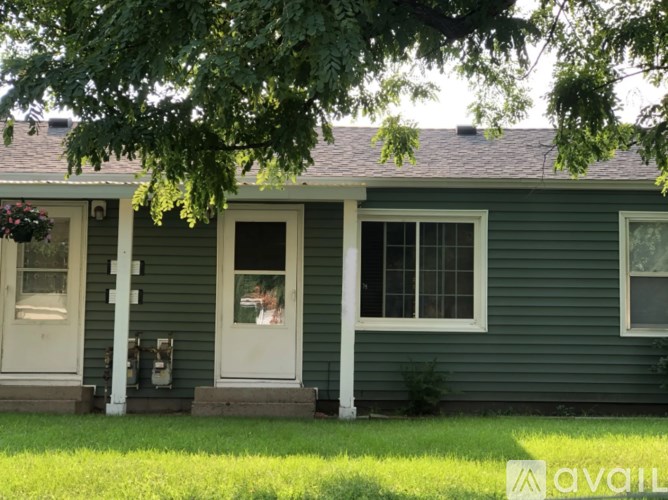 A green house with a white door and window.