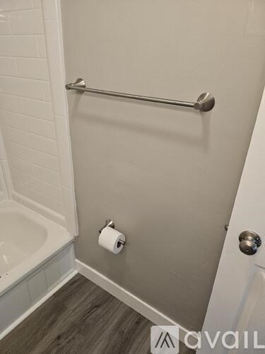 A white bathroom with a towel rack and a toilet paper roll.