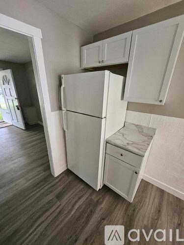 A kitchen with white cabinets and a refrigerator.