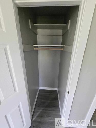 A white pantry with a door on the left and a shelf on the right.