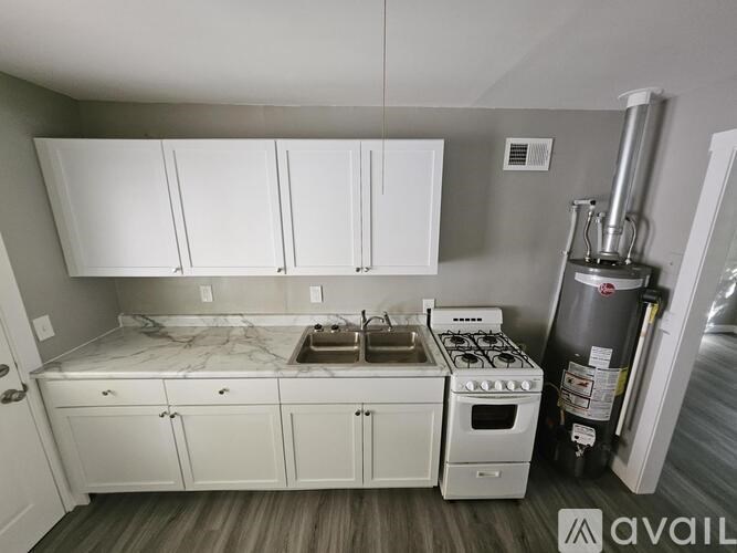 A kitchen with white cabinets and a marble countertop.