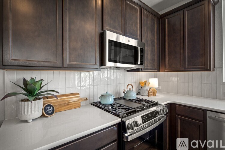 A kitchen with dark brown cabinets and a white countertop.