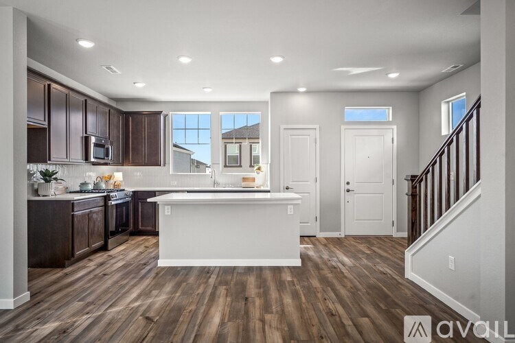 A modern kitchen with wooden floors and white countertops.