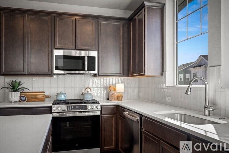 A kitchen with dark brown cabinets and a stainless steel stove top.