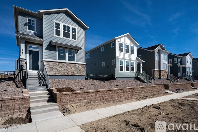 A row of houses with the first one having a stone wall and steps leading to the front door.