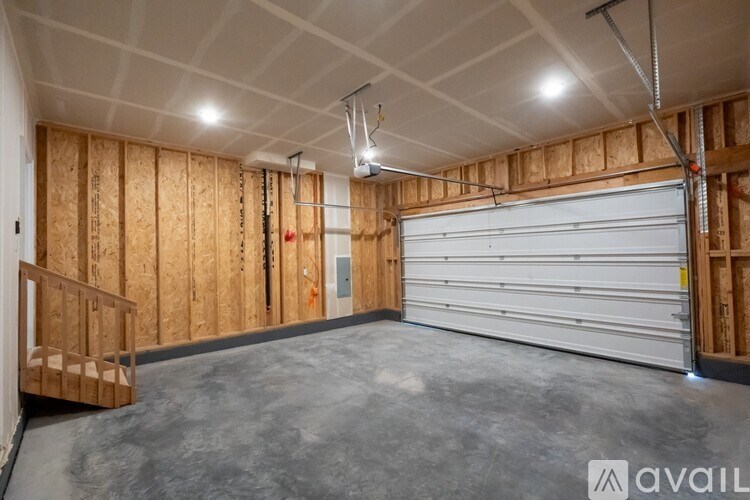 A spacious garage with a white door and wooden walls is available for rent.