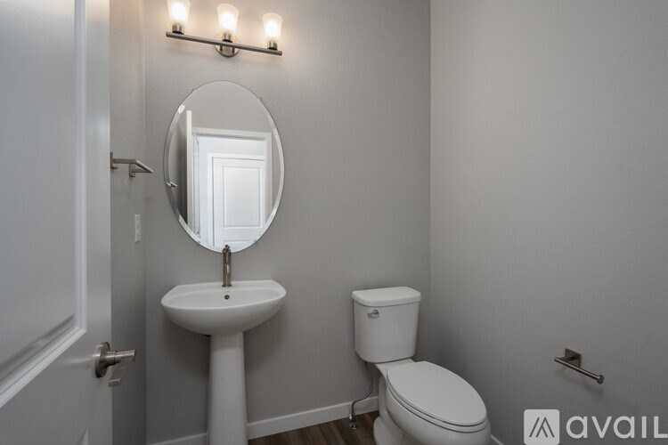 A bathroom with a toilet, sink, and mirror.