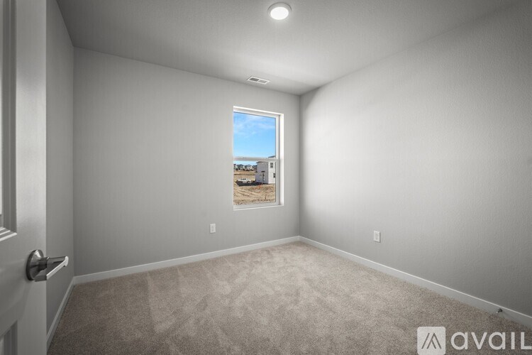 A room with a carpeted floor and a window showing a parking lot outside.